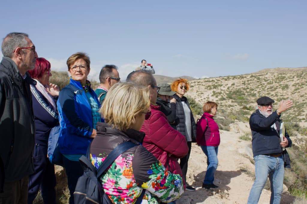 Grupo de personas escuchando al guía u observando el paisaje de La Molineta. Adriana mira a cámara.