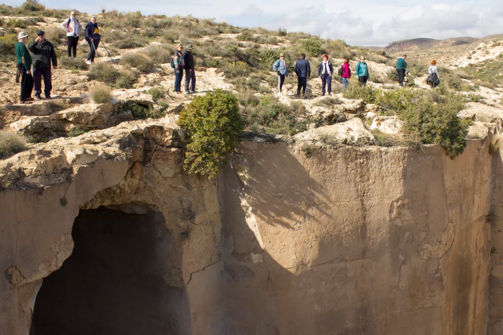 Pared vertical que forma parte de el gran depósito de agua de La Molineta. Personas pasean por un pequeño sendero en la parte superior de esta pared.