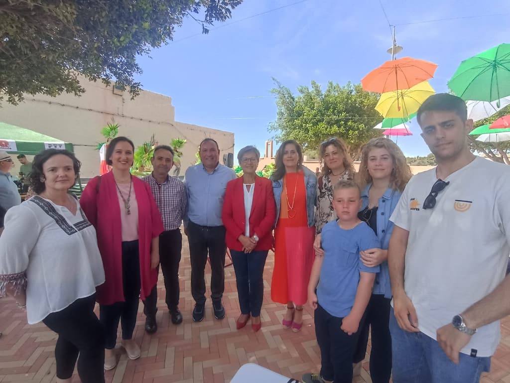 Adriana Valverde junto a miembros de su candidatura y vecinos y vecinas de Loma Cabrera bajo una alegre decoración a base de paraguas de colores.