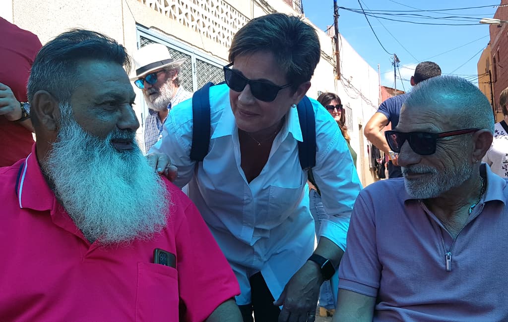 Adriana Valverde saluda a dos representantes de la comunidad gitana de Los Almendros bajo una carpa.