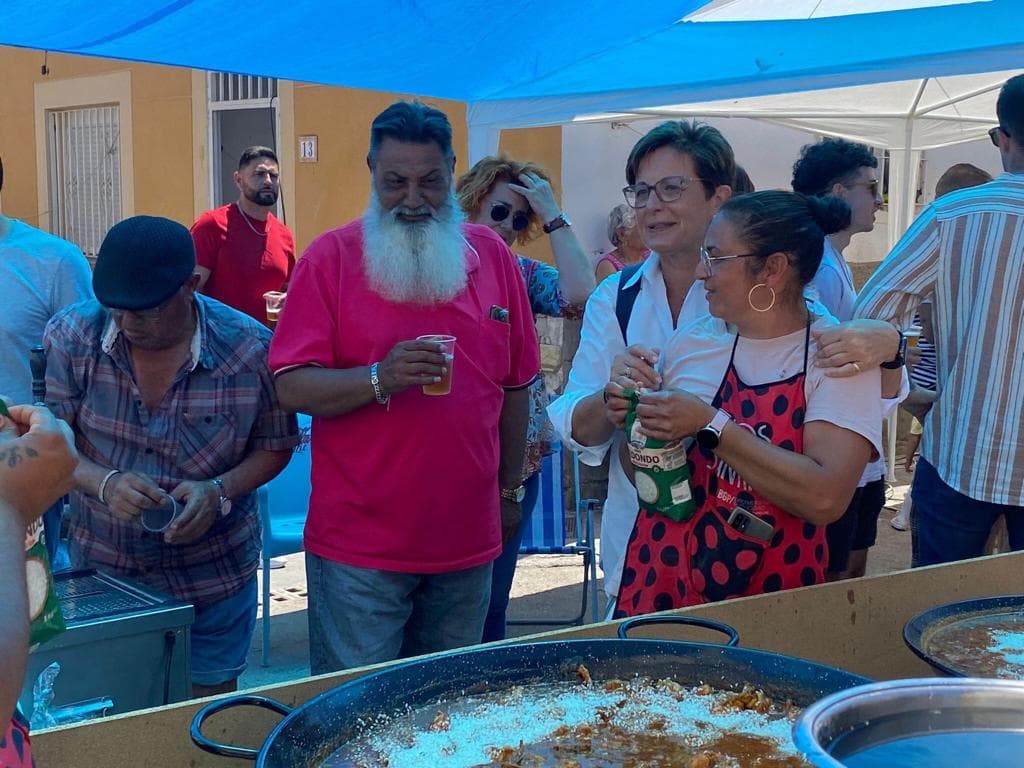 Adriana Valverde, junto a vecinos de barrio bajo el entoldado que sirvió para protegerse del sol durante la preparación de la comida.